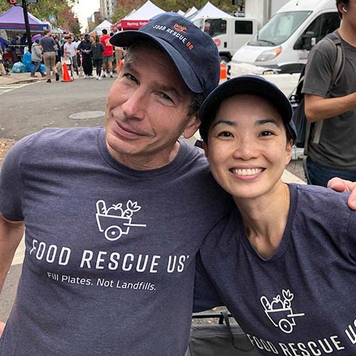 Two Food Rescue US volunteers smile together at the farmers market