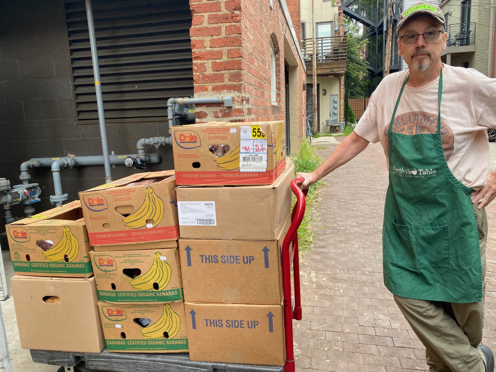 A man stands with a cart loaded with boxes of recovered food