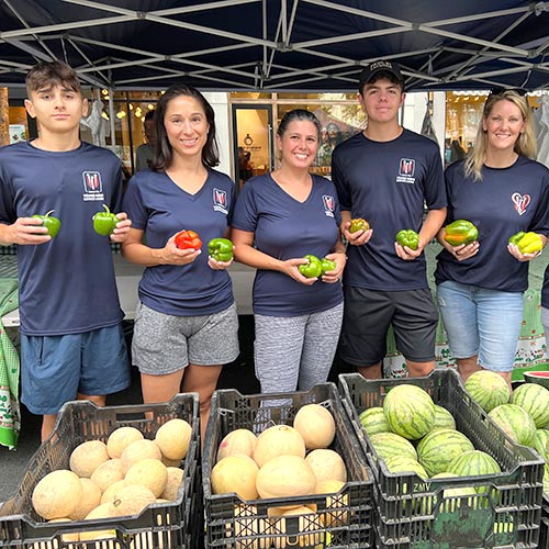 A group of volunteers pose with rescued produce at a farmers market