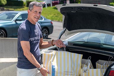 Connecticut volunteer Oliver Kaufman places bags of rescued food into the trunk of his car