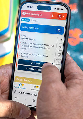 Close-up view of a volunteer using the Food Rescue US app on his phone