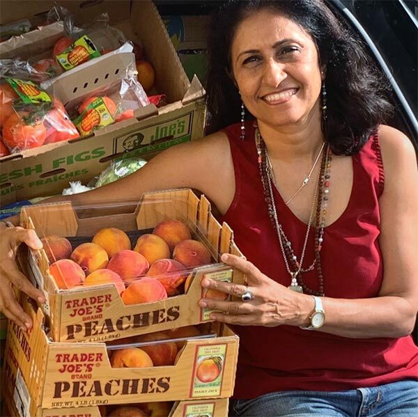 A volunteer sits next to boxes of rescued peaches